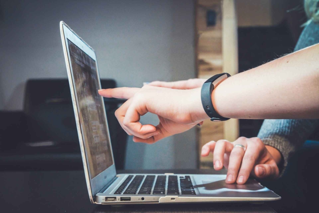 Hands pointing at a laptop screen