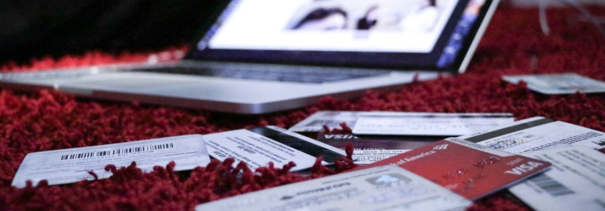 Laptop and multiple credit cards strewn on a bed